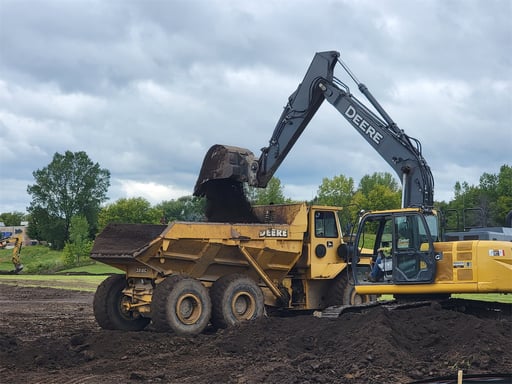 excavator filling a dumptruck with dirt